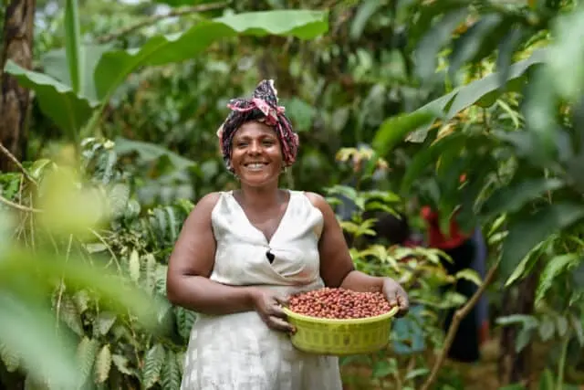 Grace, a coffee farmer from western Uganda, holding harvested coffee cherries